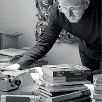 Raoul Eisele beugt sich über Bücherstapel und eine Schreibmaschine, Schwarzweißfoto
