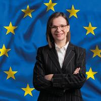 Prof.in Gerda Füricht-Fiegl mit verschränkten Armen vor der Europaflagge